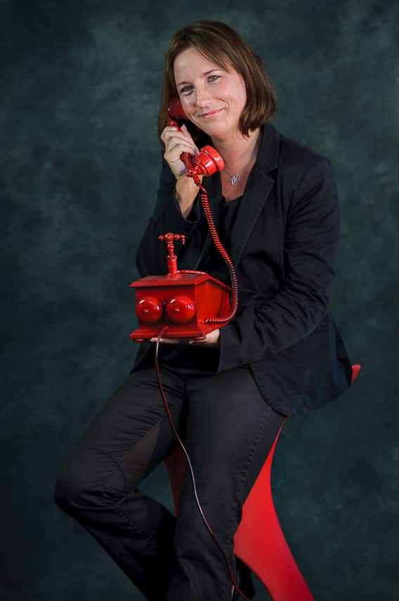 Portrait couleur d'une jeune femme avec un téléphone rouge à la main