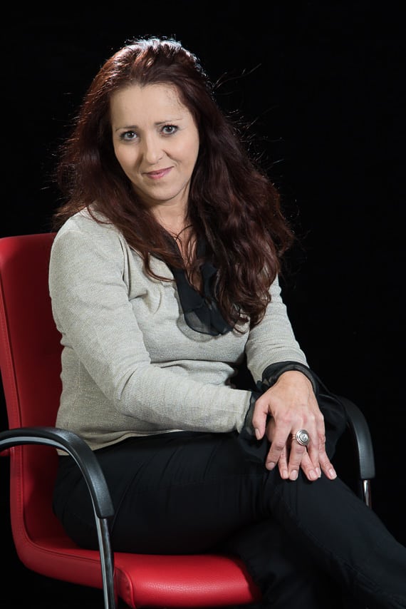 Portrait couleur d'une collaboratrice assise sur une chaise rouge